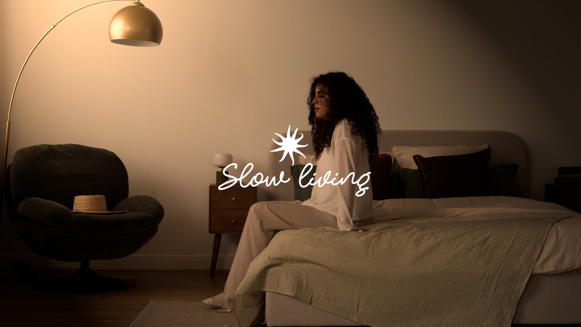Chambre slow living, linge de lit coton rayé vert, table de chevet vintage en bois, lumière tamisée dorée – Maison Pavane