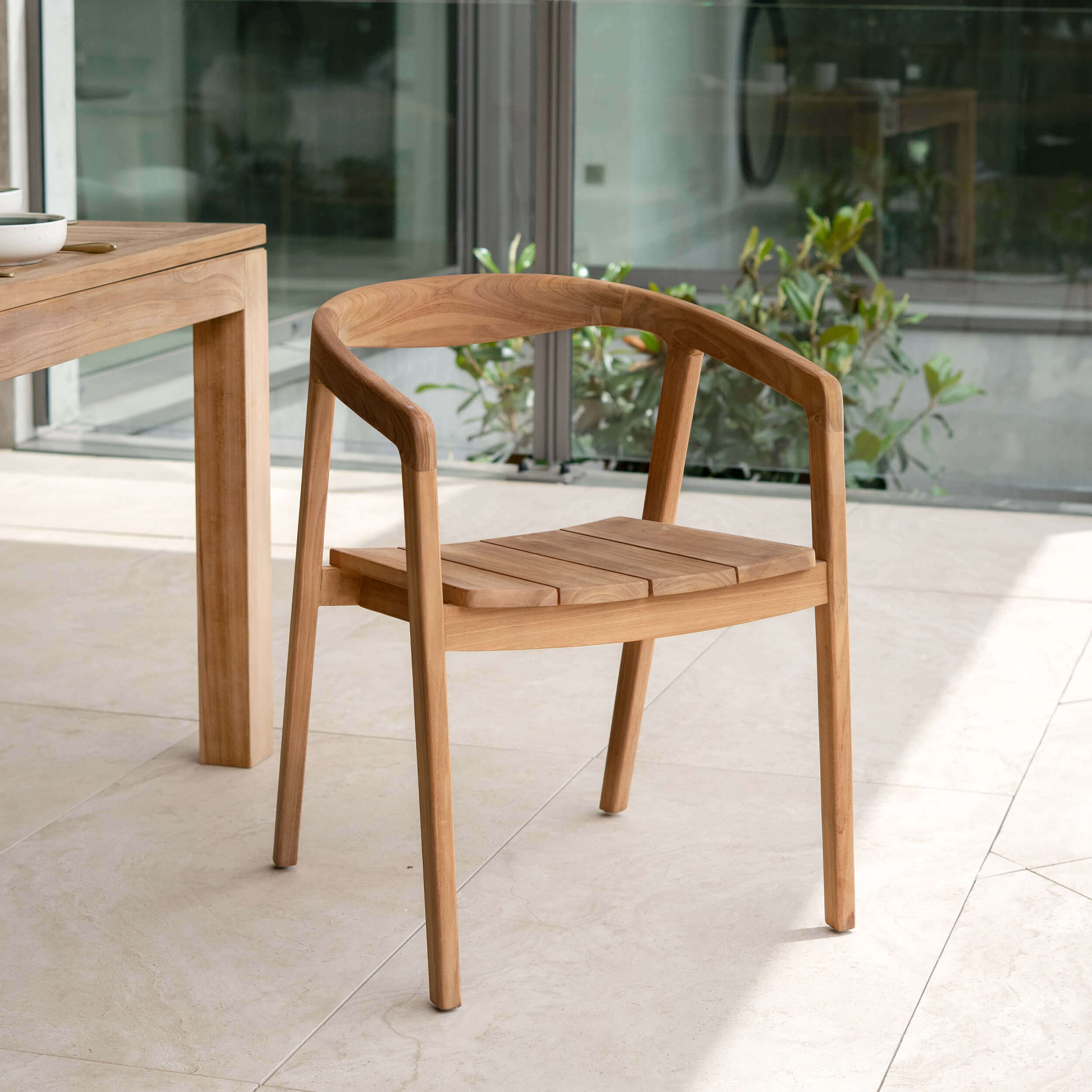Chaise avec accoudoirs en teck massif, design épuré scandinave, terrasse lumineuse avec végétation – Maison Pavane