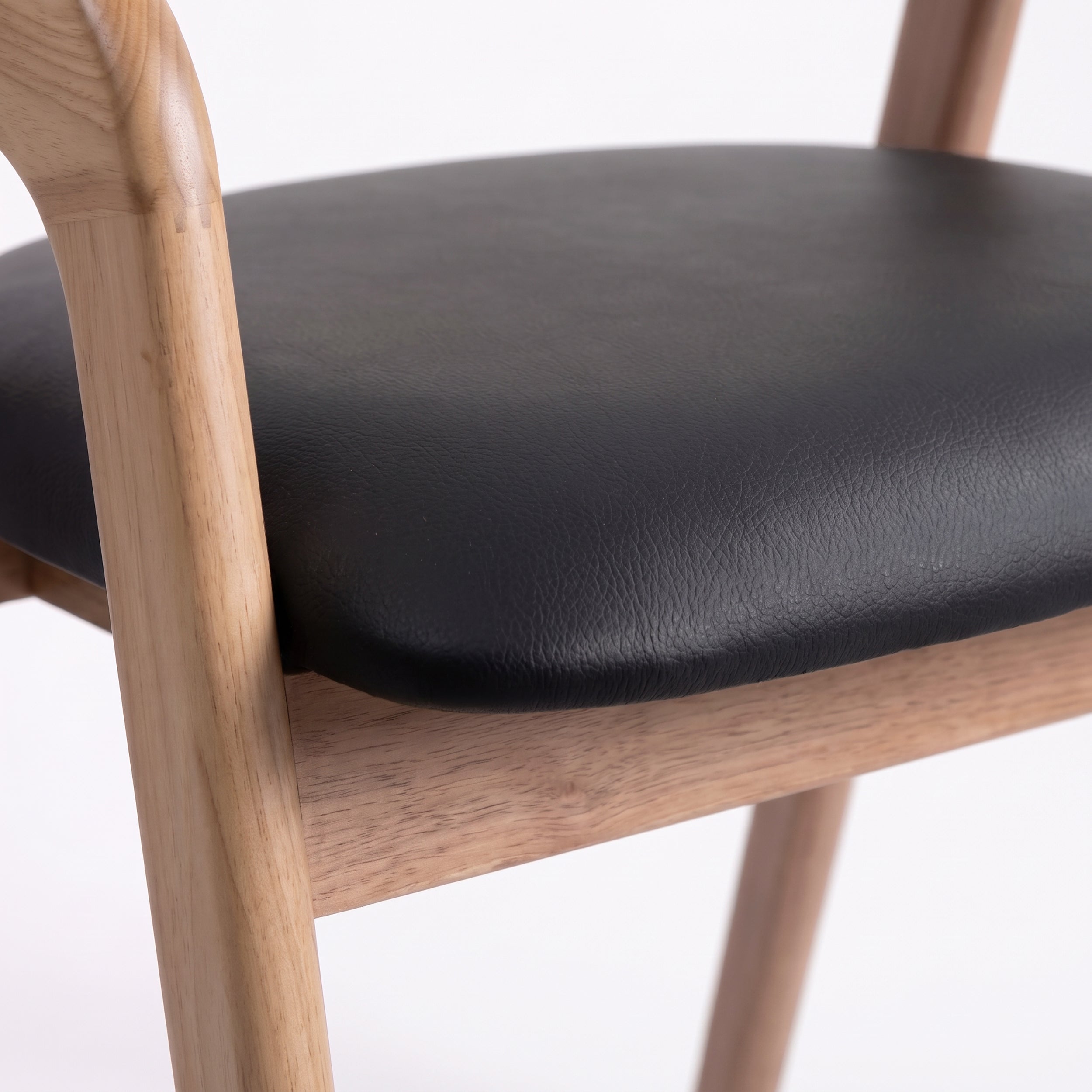 Détail de l'assise en cuir synthétique noir de la chaise Hawa en bois blond - Maison Pavane