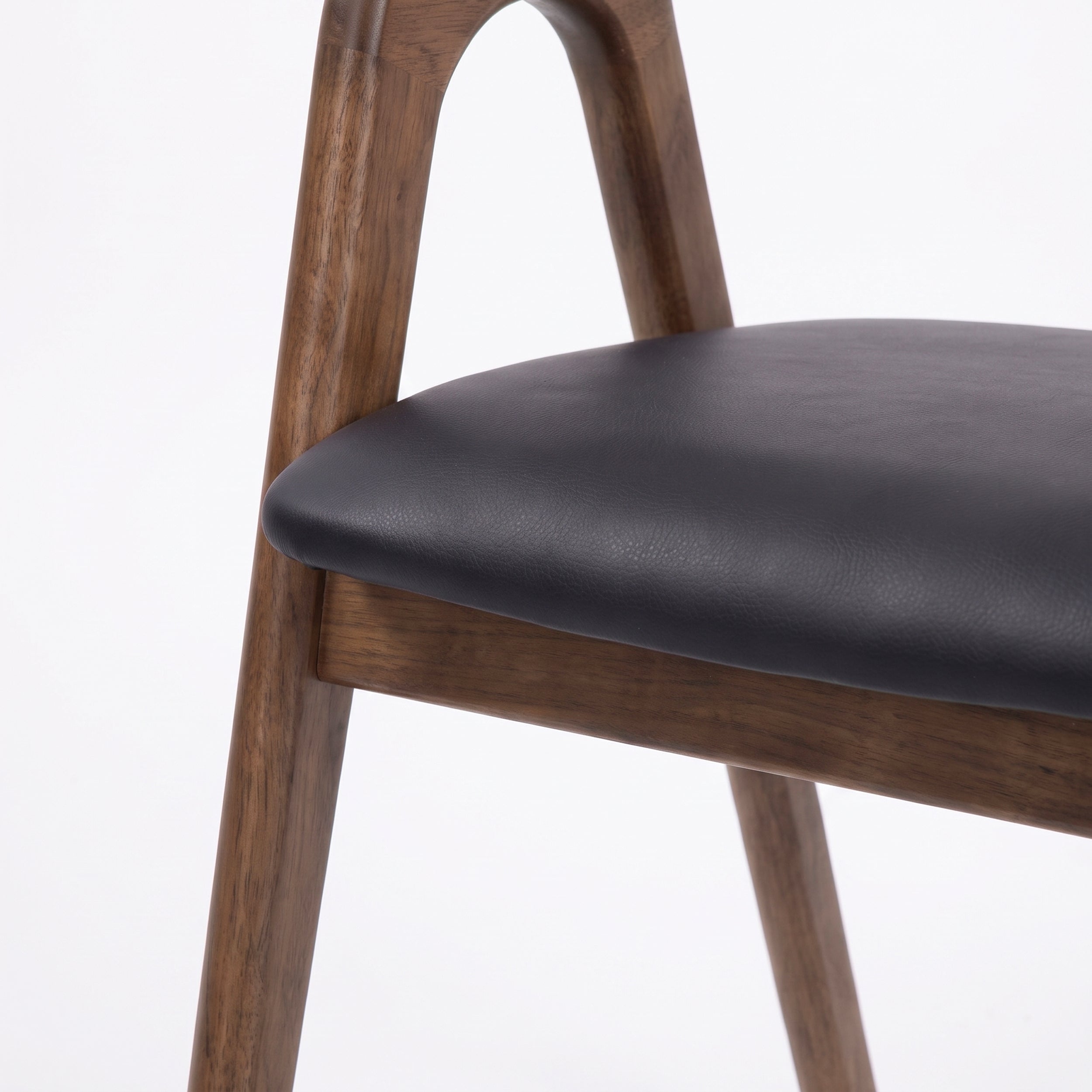 Détail de l'assise en cuir synthétique noir de la chaise Hawa en bois d'hévéa marron - Maison Pavane