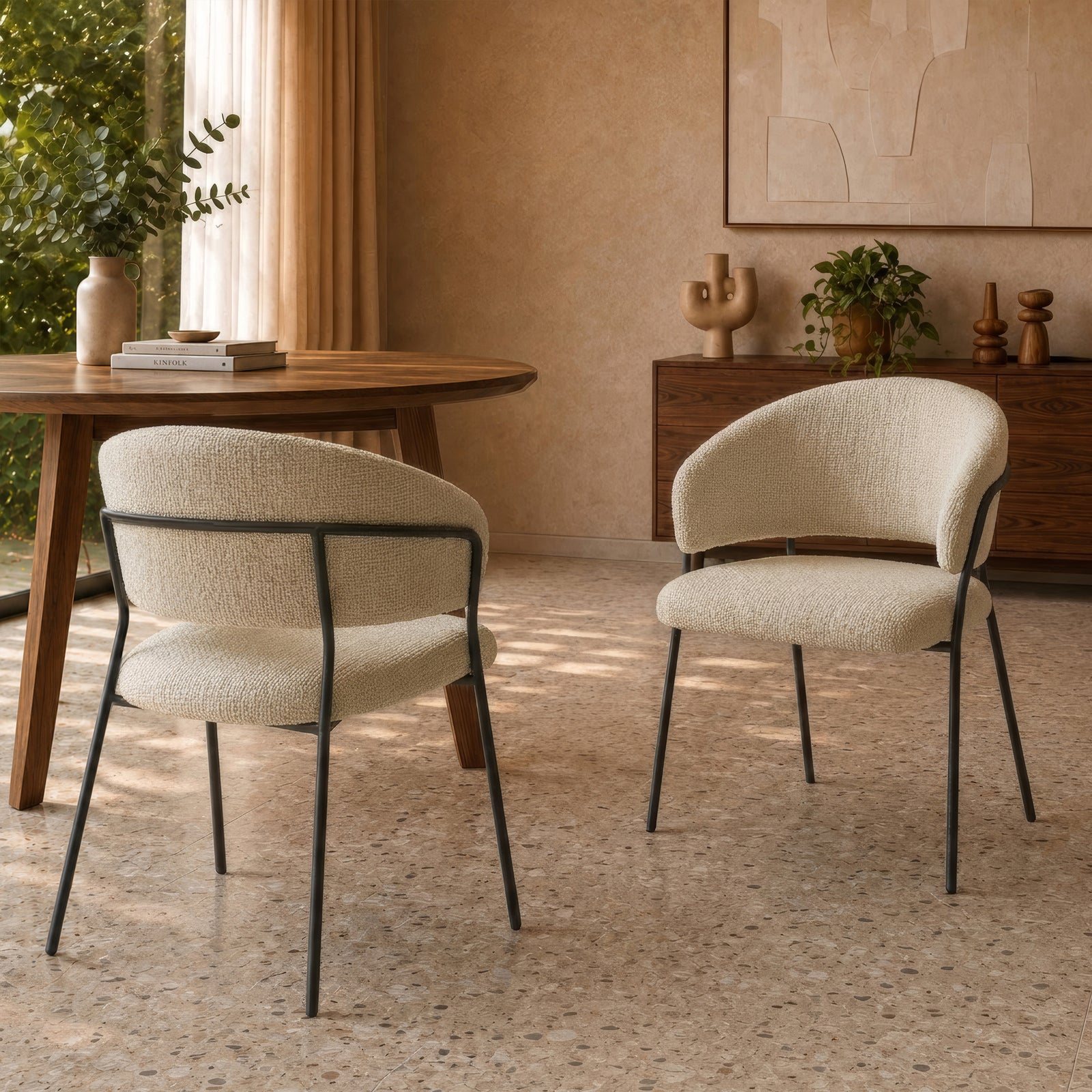 Lot de 2 chaises Amaya en tissu bouclette beige et pieds en métal noir, autour d'une table ronde en bois dans une salle à manger au sol terrazzo