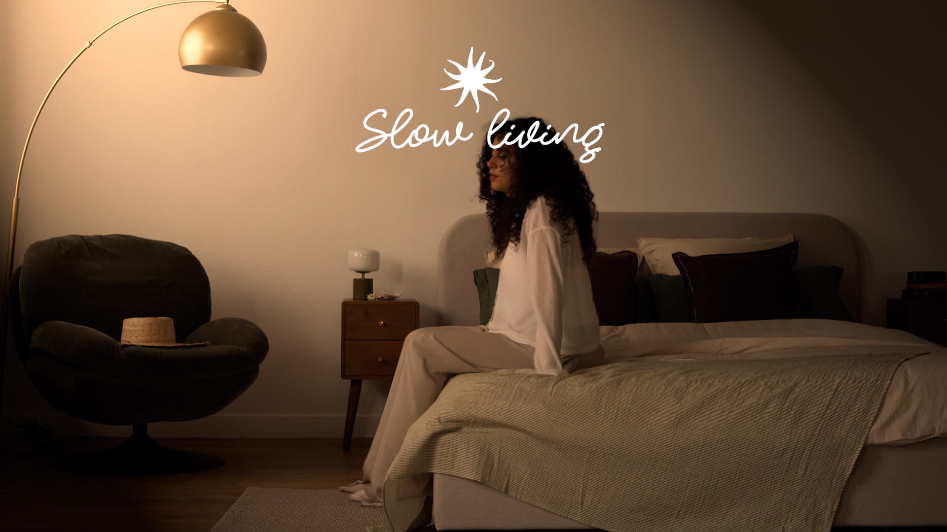 Chambre slow living, linge de lit coton rayé vert, table de chevet vintage en bois, lumière tamisée dorée – Maison Pavane