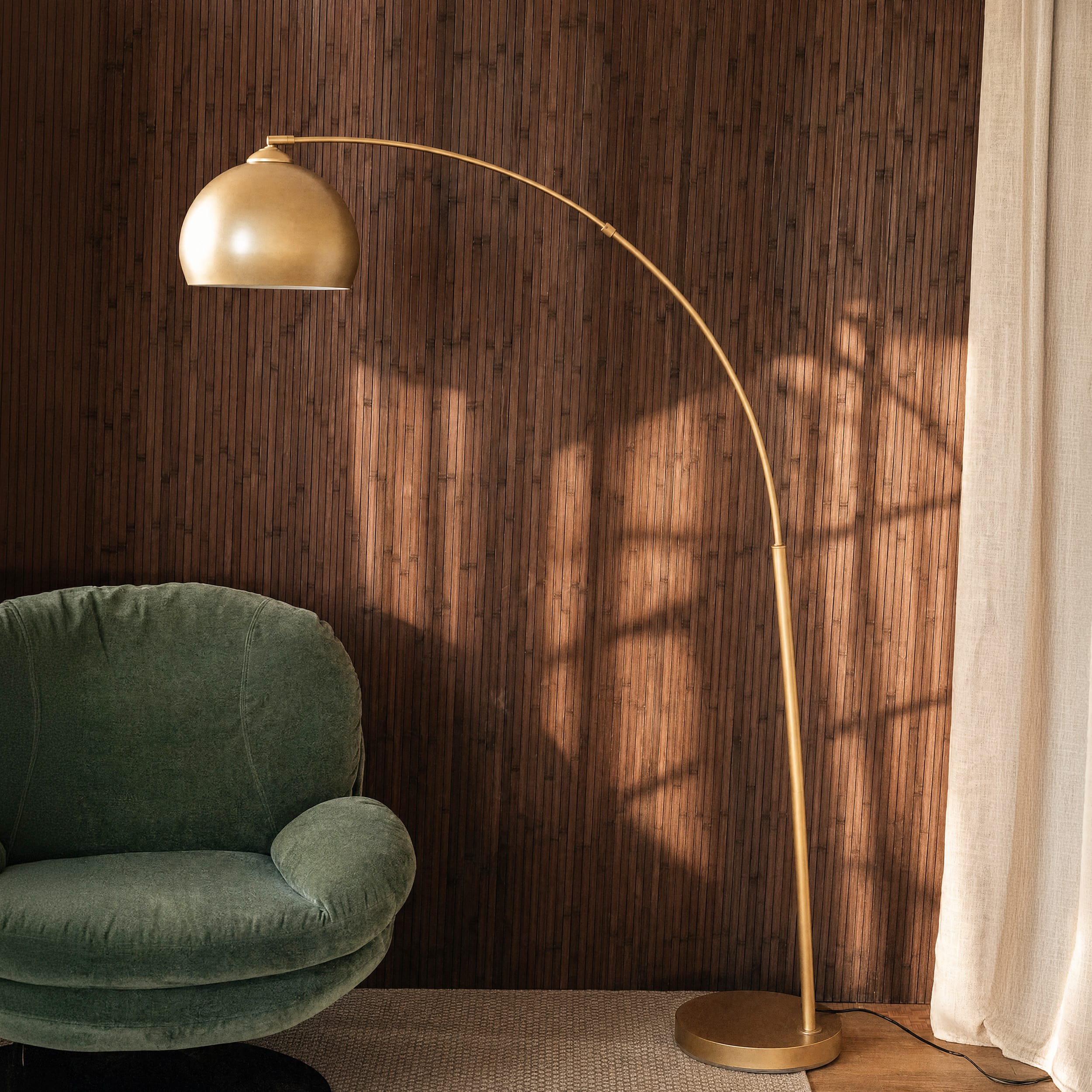 Lampadaire arc en métal laiton doré, abat-jour demi-sphère, ambiance chaleureuse avec fauteuil velours vert – Maison Pavane