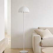 Lampadaire Flow en métal blanc, dans un salon lumineux à côté d'un canapé beige et d'un banc en bois clair