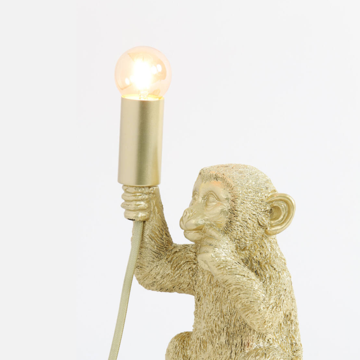 Détail de la douille et de l'ampoule de la lampe à poser Monkey en plastique doré - Maison Pavane