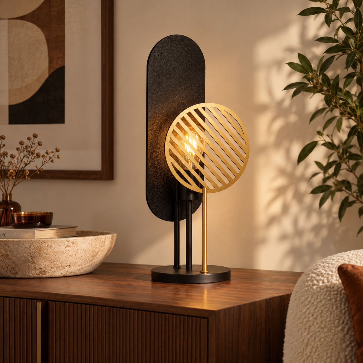 Lampe à poser Totem en métal noir et doré H45 cm, allumée sur un buffet en bois entouré de plantes