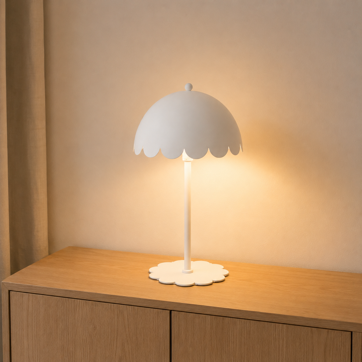 Lampe à poser Flow en métal blanc, allumée sur un buffet en bois clair devant un mur beige