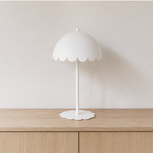 Lampe à poser Flow en métal blanc, éteinte sur un buffet en bois clair devant un mur beige en lumière naturelle
