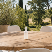Petite lampe nomade Elo en plastique blanc, posée sur une table en bois d'une terrasse à la campagne