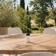 Petite lampe nomade Elo en plastique noir, posée sur une table en bois d'une terrasse à la campagne
