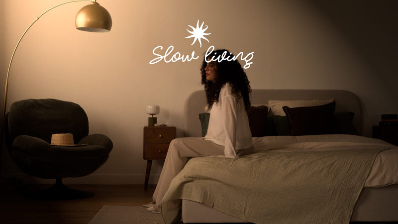 Chambre slow living avec lit en lin sage, lampadaire doré et fauteuil velours anthracite, ambiance tamisée et cosy – Maison Pavane