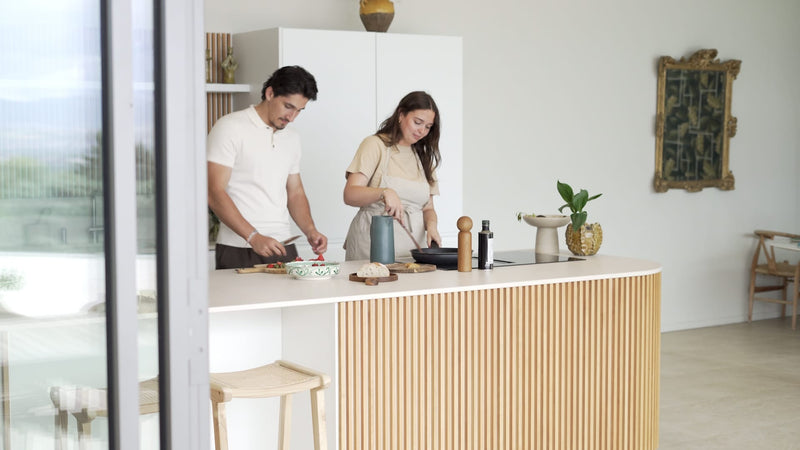 Couple préparant un repas dans une cuisine lumineuse avec îlot bois cannelé – Soldes Maison Pavane