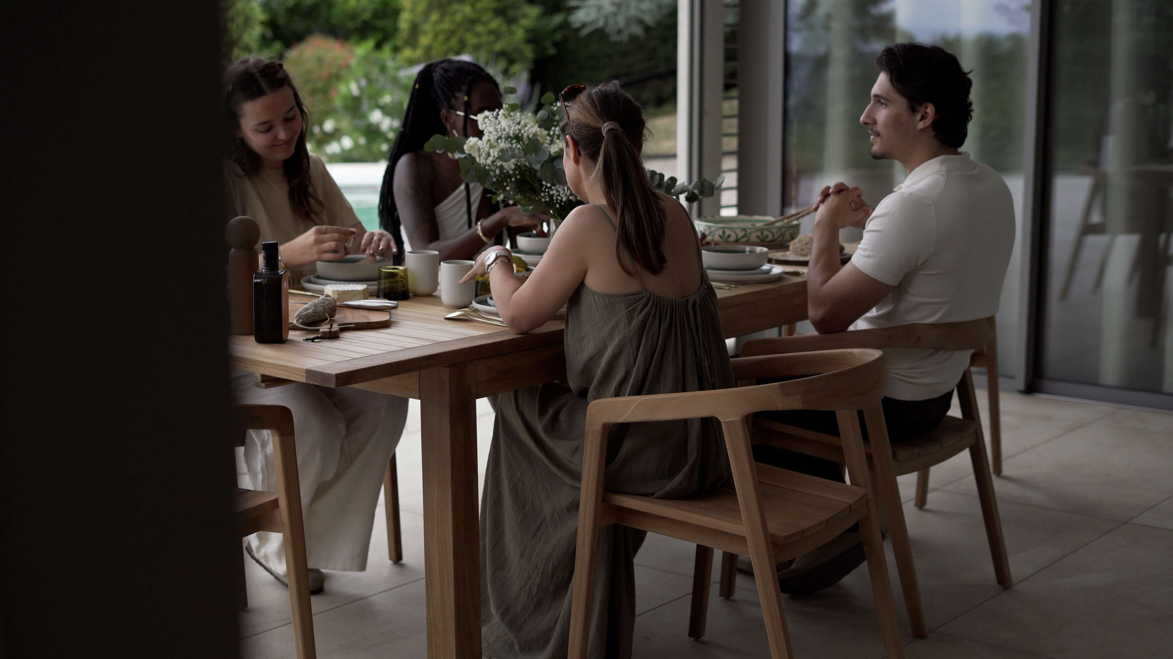 Table et chaises de repas extérieur en bois teck naturel, ambiance conviviale en terrasse lumineuse – Maison Pavane