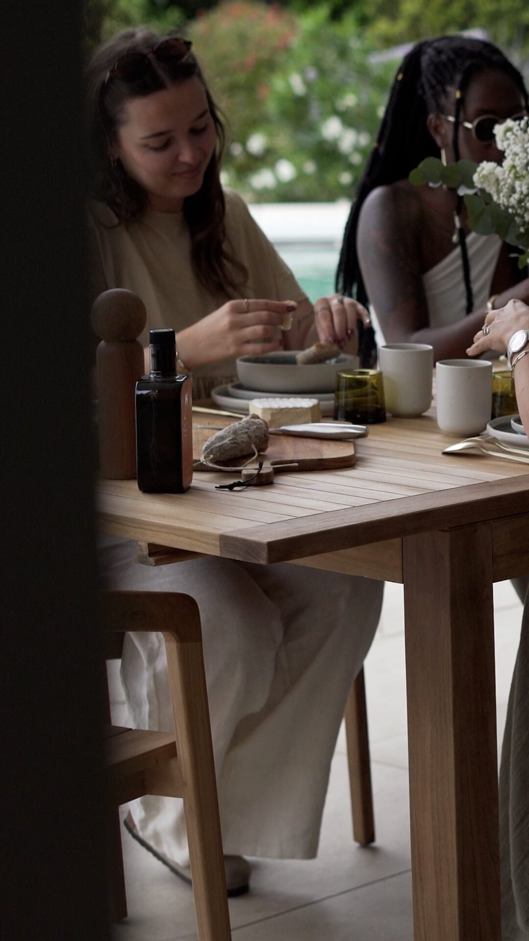 Table de repas extérieure en bois clair avec vaisselle minimaliste, ambiance déjeuner estival en terrasse – Maison Pavane