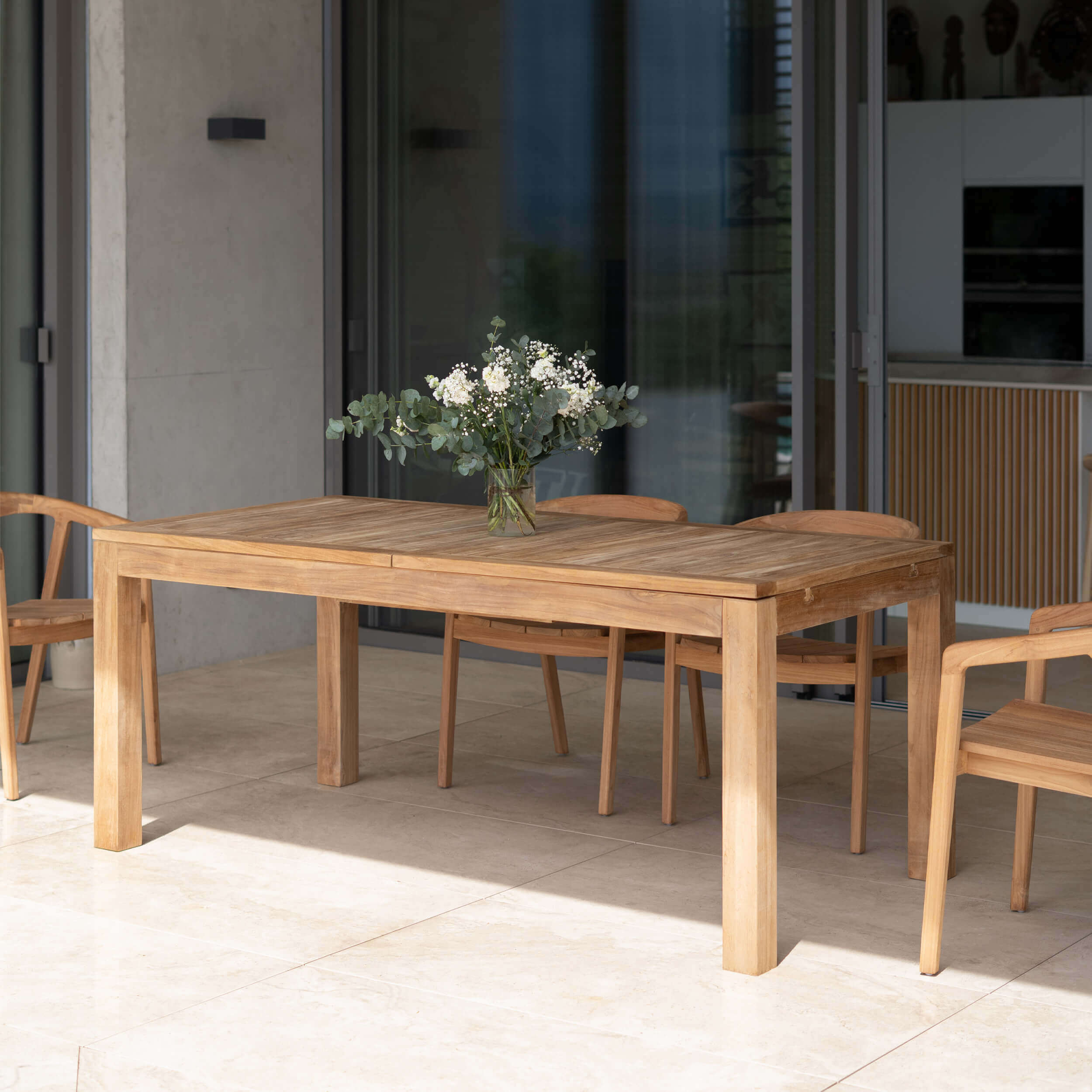 Table extensible en teck naturel avec chaises assorties sur terrasse ensoleillée, ambiance scandinave épurée – Maison Pavane