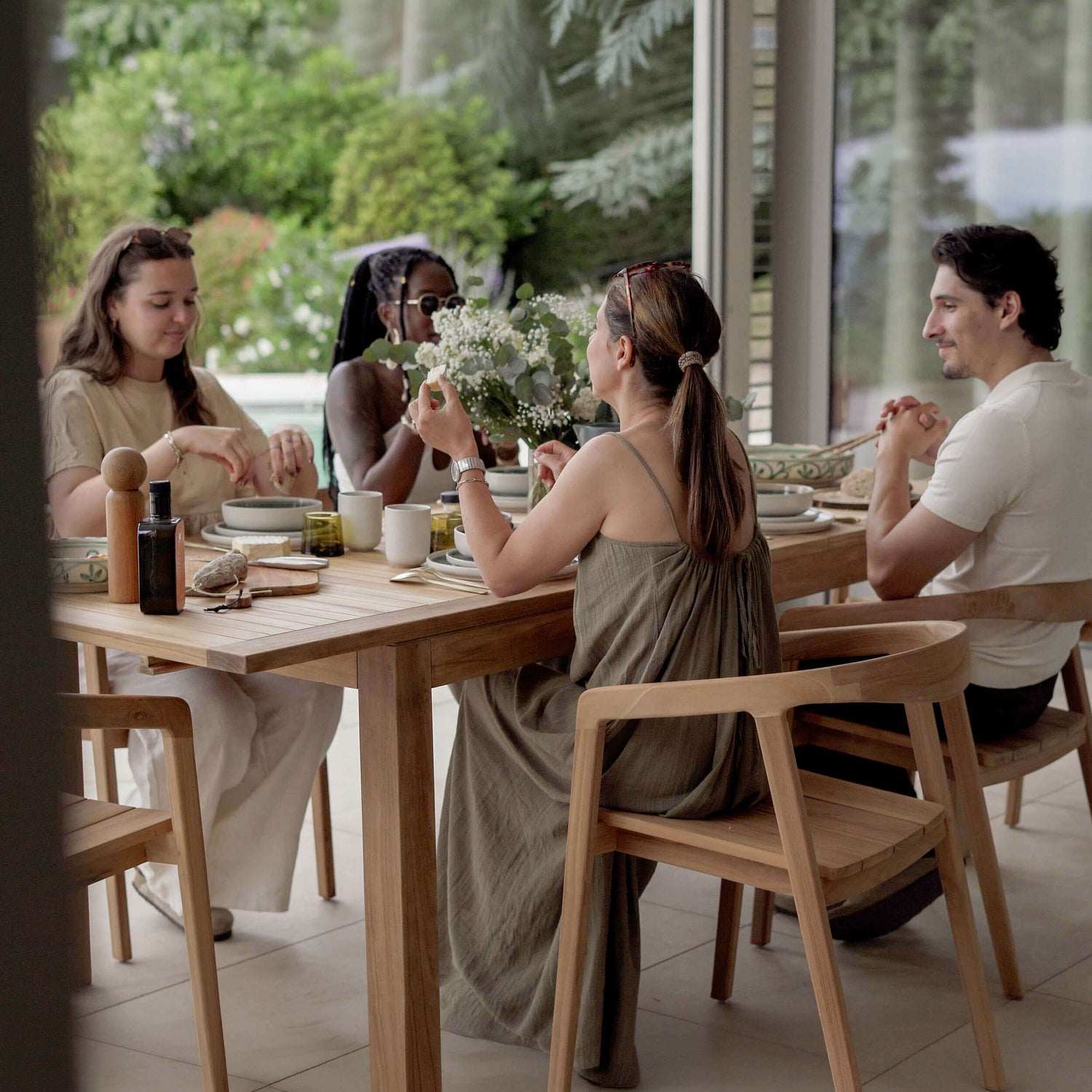 Table et chaises en teck naturel style scandinave, repas convivial en terrasse lumineuse entourée de verdure – Maison Pavane