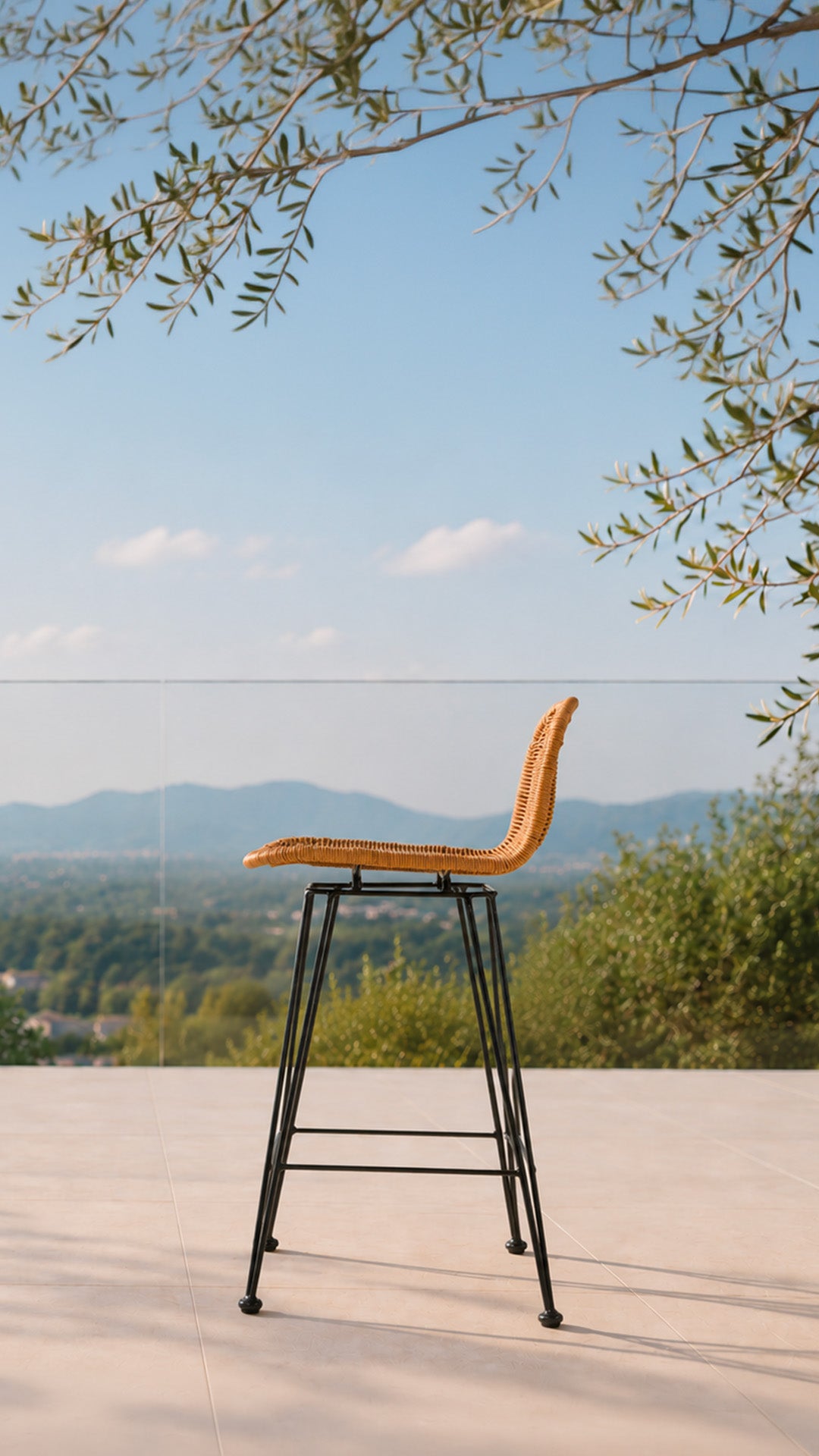 Tabouret de bar en rotin avec pieds en métal noir sur une terrasse avec une piscine en plein été - Maison Pavane